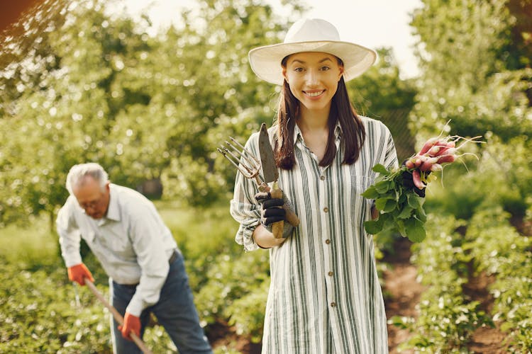 Photo Of A Woman With A Hat Holding Radishes