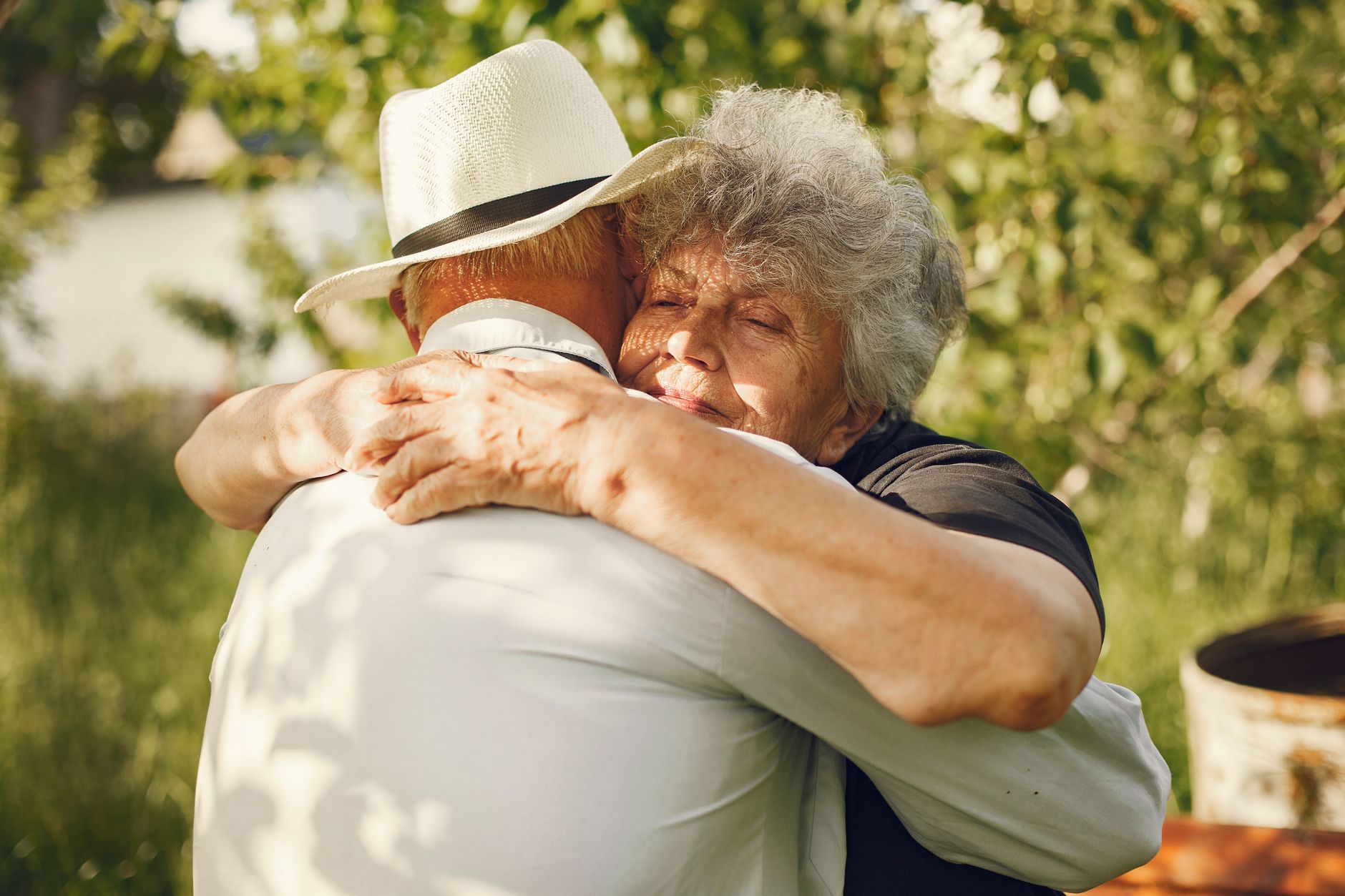 mebendazole cancer support dosing in older adults — An elderly couple sharing a warm embrace in a sunny outdoor setting.
