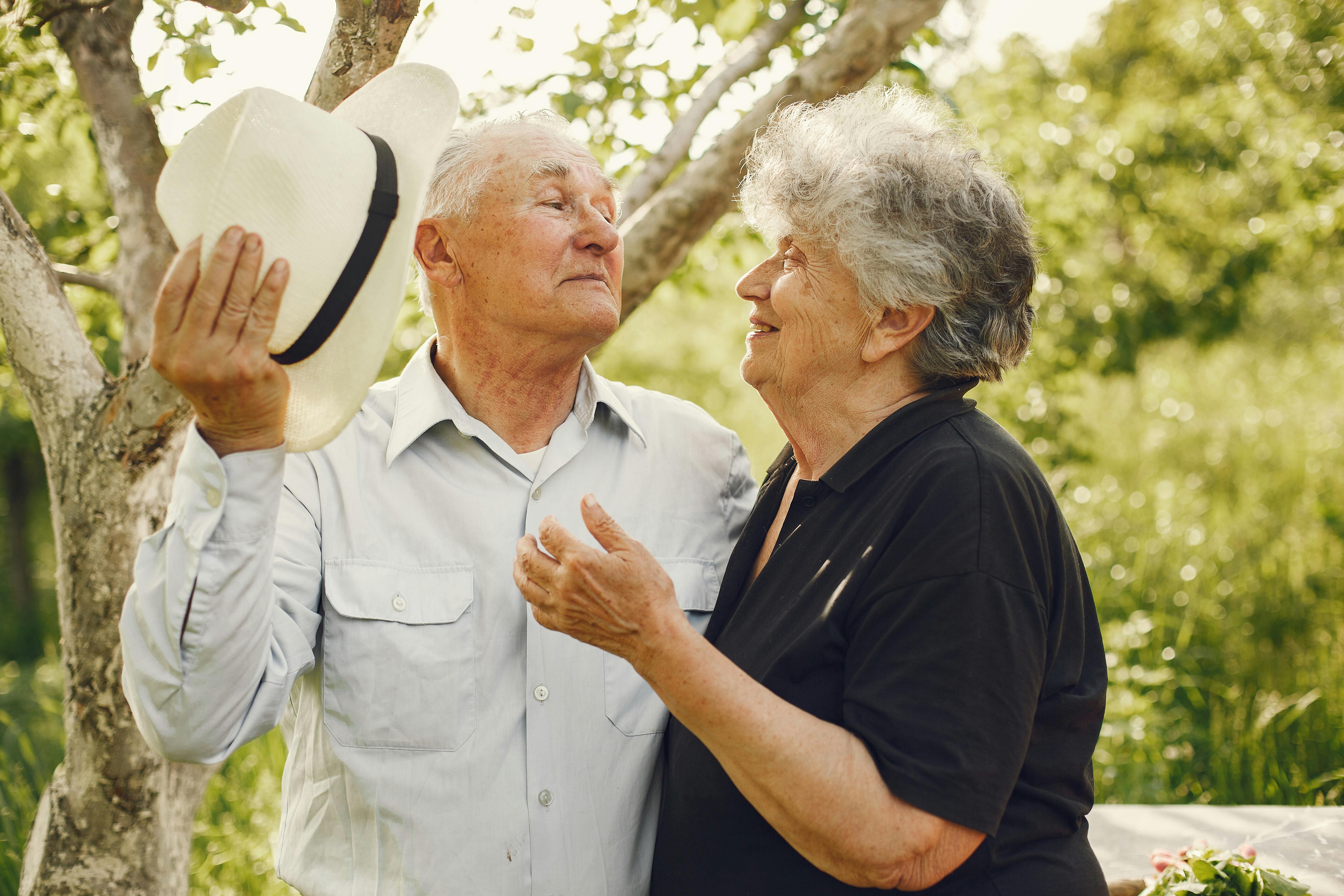 Charming elderly couple sharing a joyful moment outdoors in the summer sun.