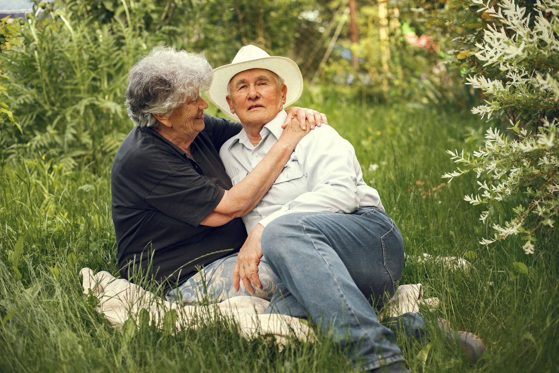 An elderly couple embraces in a lush garden, capturing a moment of love and serenity.