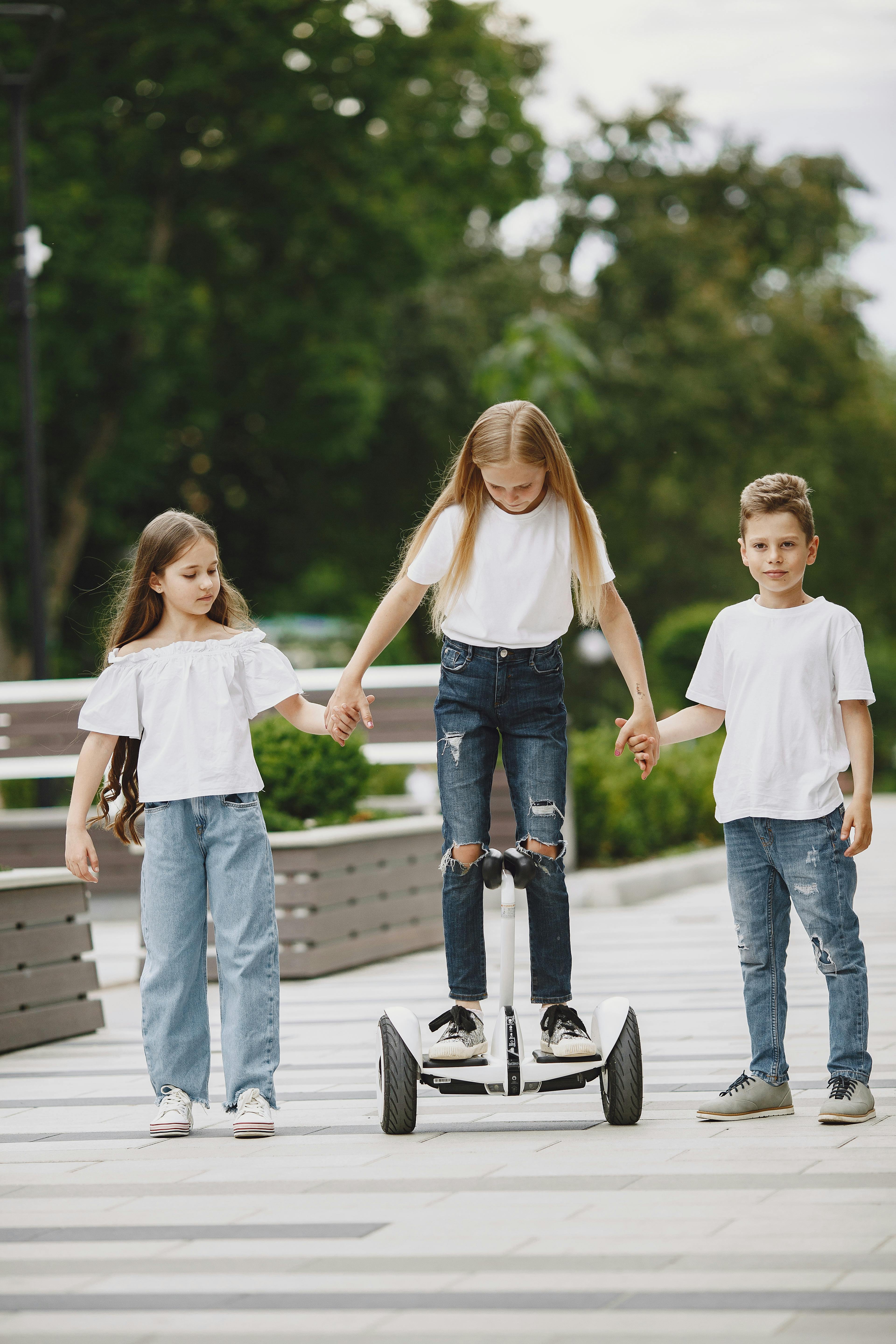 girl on balancing scooter holding hands with friends