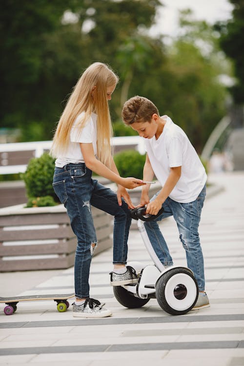 Free Girl and Boy with Skateboard and Electric Scooter Stock Photo