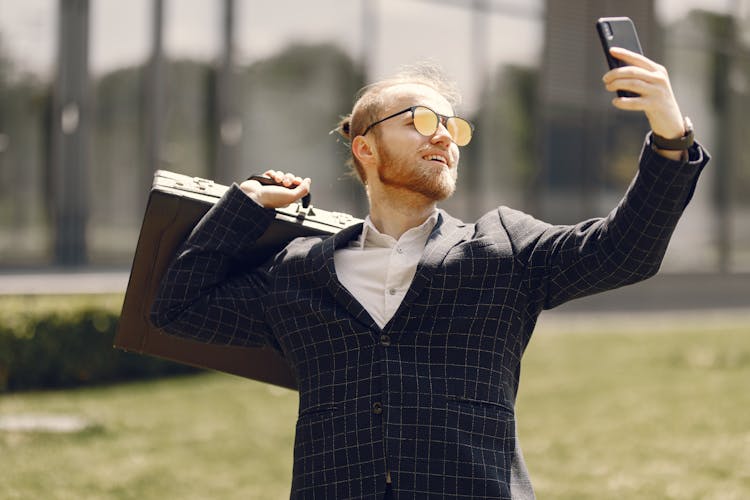 A Bearded Man Holding A Briefcase While Taking A Selfie