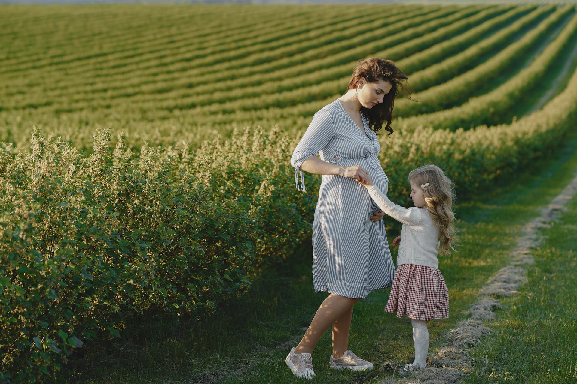 Mother and daughter bonding in a lush agricultural field, symbolizing new beginnings and family love.