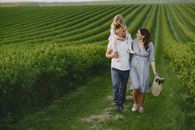 Man and Woman Holding Hands While Walking on Green Grass Field