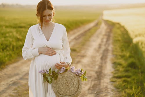 Free A Pregnant Woman with a Bag of Flowers Holding Her Belly Stock Photo