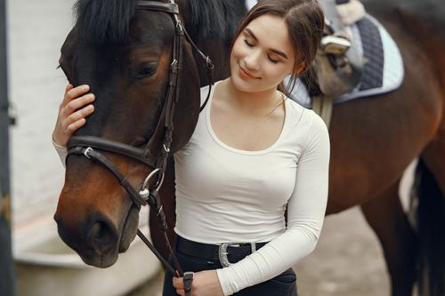 Free Young woman tenderly petting a horse, showcasing a bond between animal and human. Stock Photo