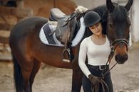 Woman in White Long Sleeve Shirt Riding Brown Horse