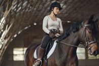 Woman in White Long Sleeve Shirt Riding Black Horse
