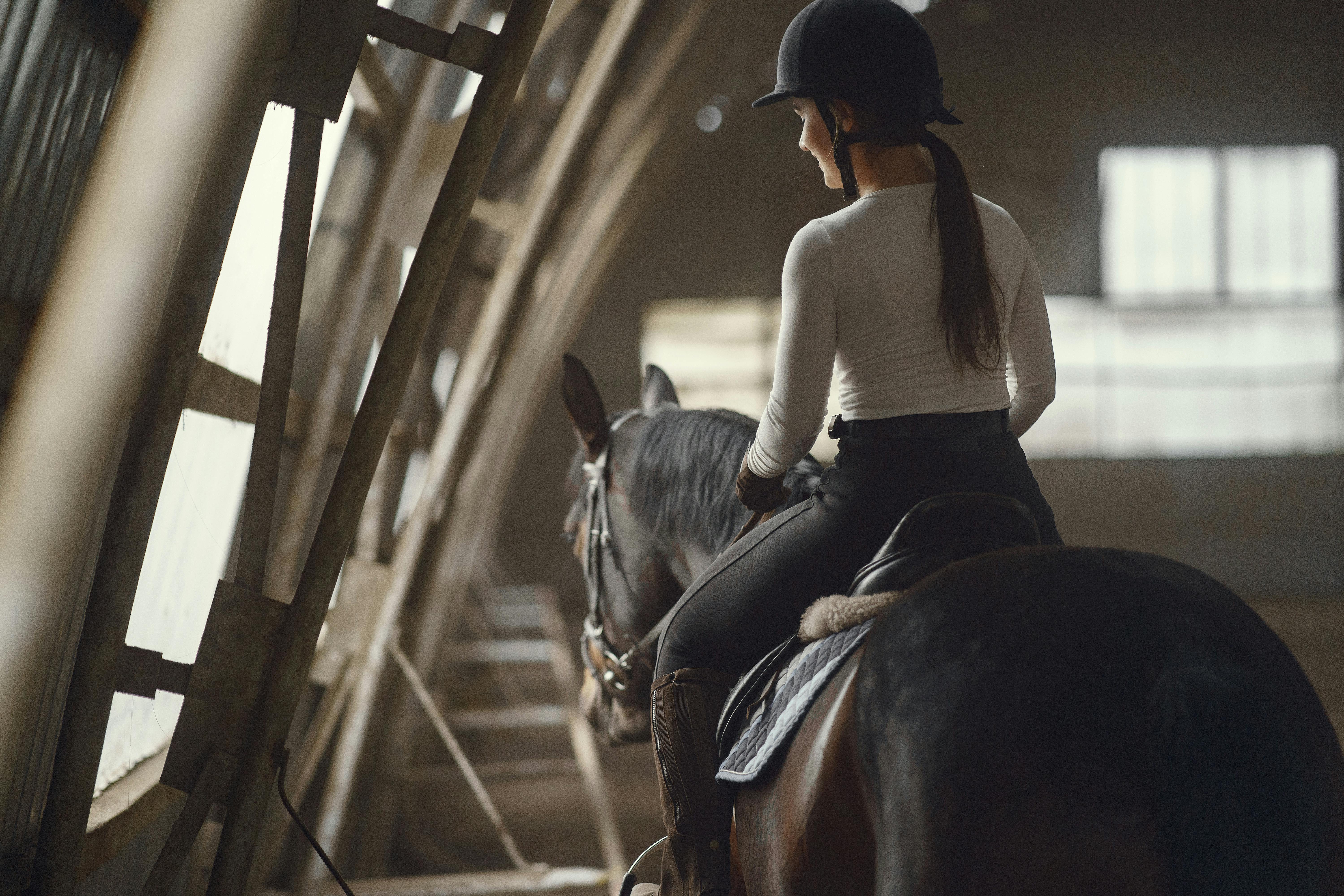 woman wearing a helmet while riding a horse