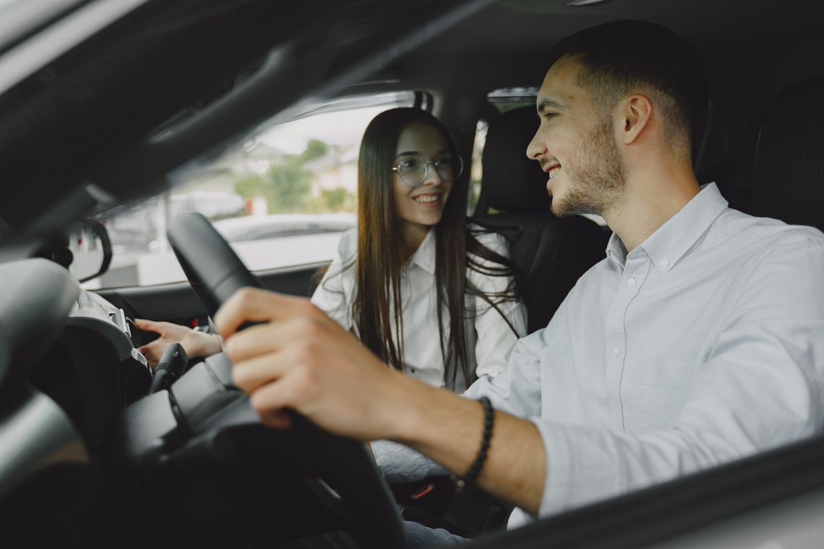 Instruktorius ir mokinė automobilyje aptaria pirmąją pamoką