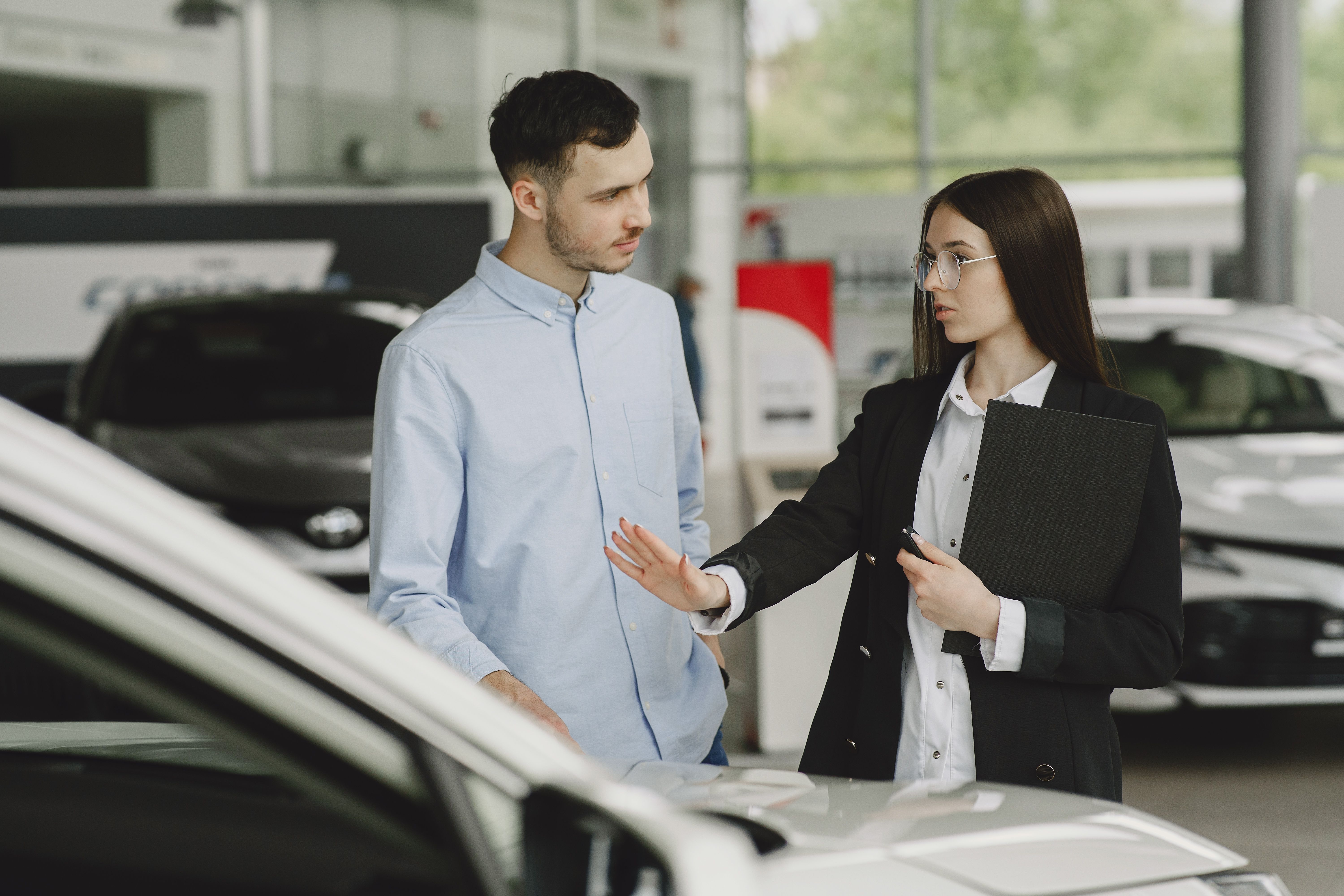 Women explaining to man in car dealership