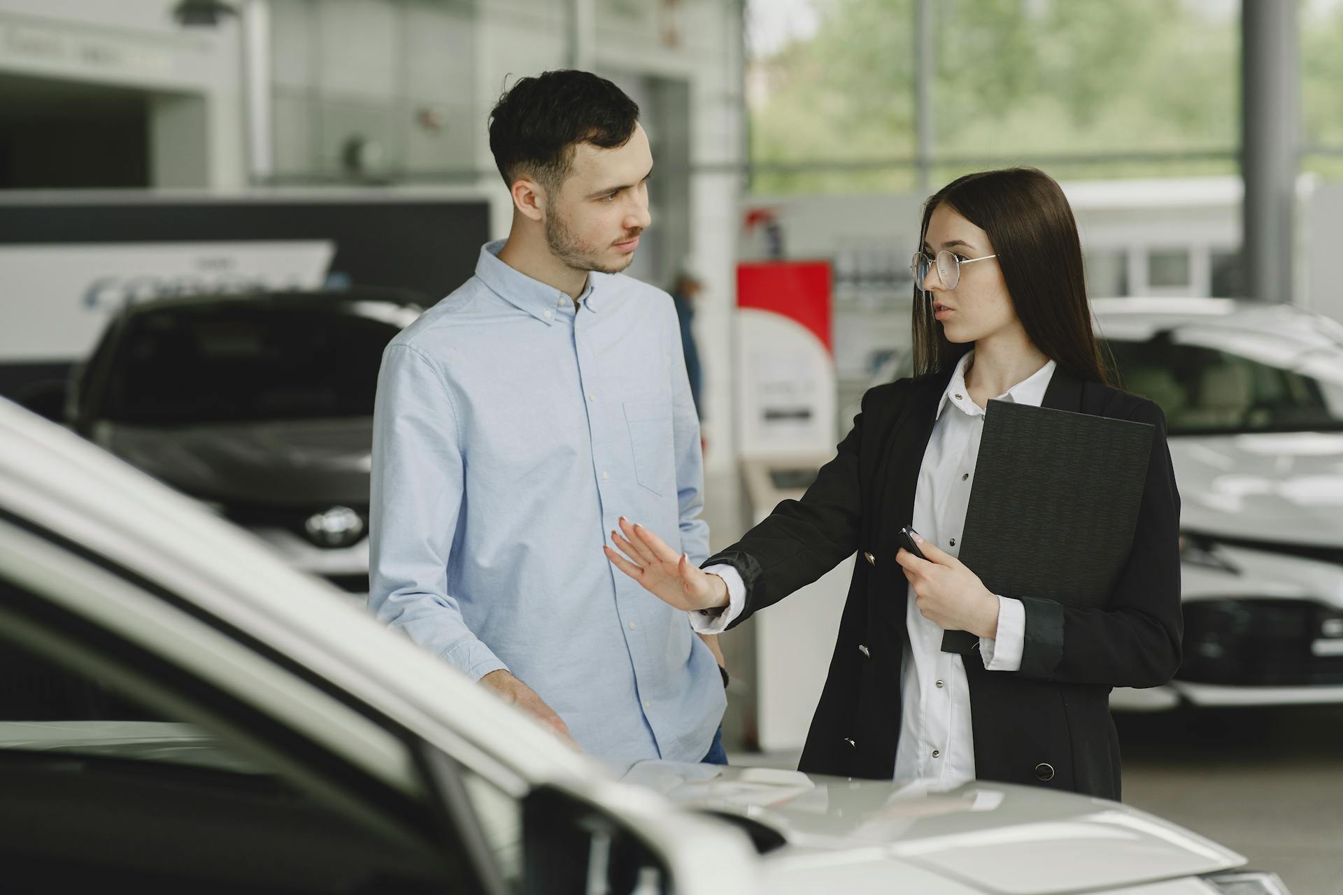 A salesperson and customer discussing car features in a dealership setting.