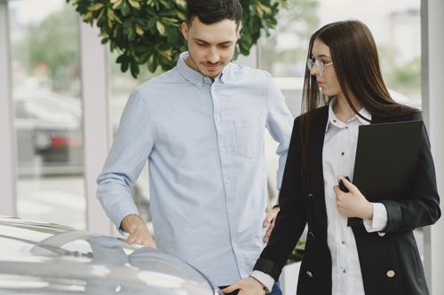 Free Professional interaction between a client and salesperson in a car dealership setting. Stock Photo