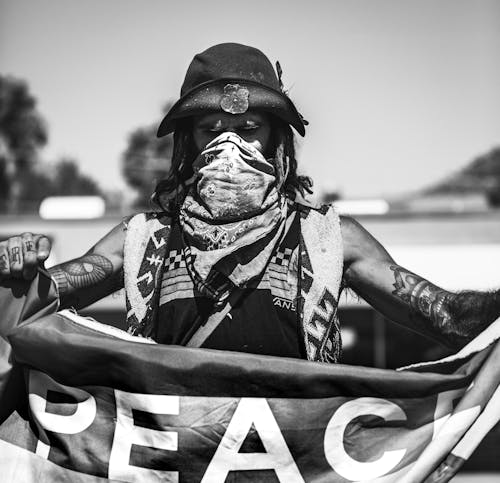 Black and White Photo of Man Holding Peace Flag