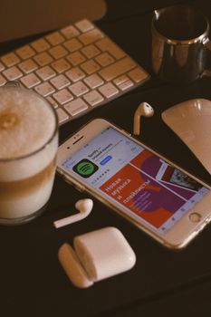 Coffee, smartphone with Spotify app, and gadgets on a desk, perfect for tech and lifestyle themes.