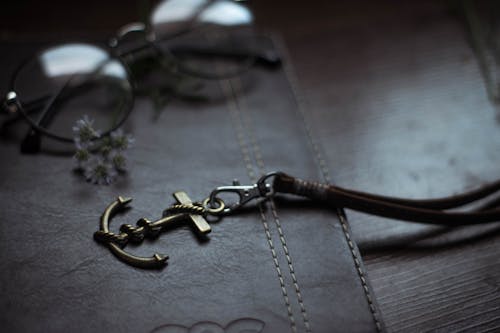 Free Anchor shaped pendant on leather diary near eyeglasses Stock Photo