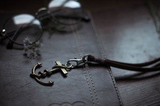 Anchor shaped pendant on leather diary near eyeglasses
