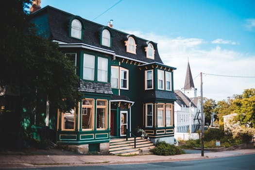 A picturesque Victorian house with green facade on a sunny day in a serene neighborhood.