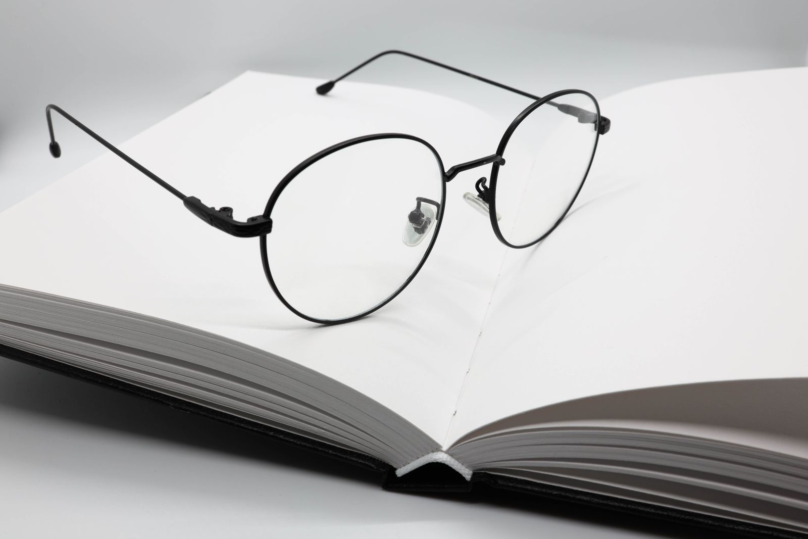 Black wire-rim glasses resting on a blank open book