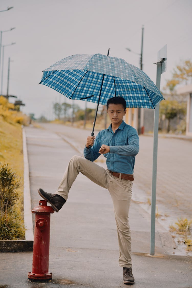 A Man Holding An Umbrella While Looking At The Time