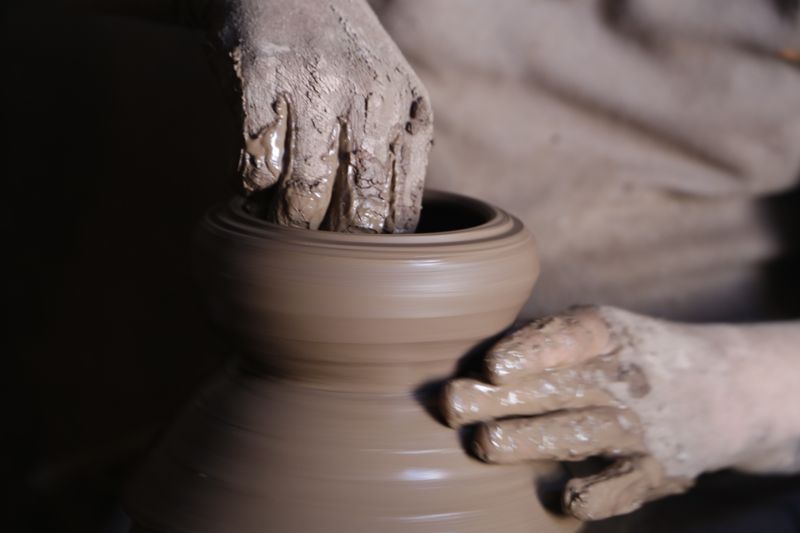 Artisan manually kneading and wedging Zisha clay on a stone workbench to remove air bubbles and achieve uniform consistency
