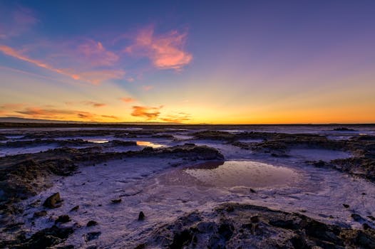 Stunning sunset over rocky tidal flats with vibrant skies in San Jose, California.