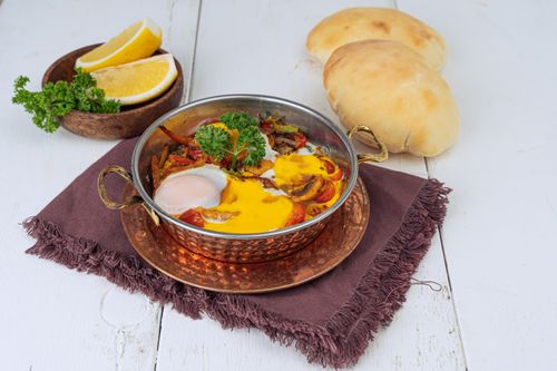 Free Savory Middle Eastern shakshuka served with pita bread and lemon slices. Stock Photo
