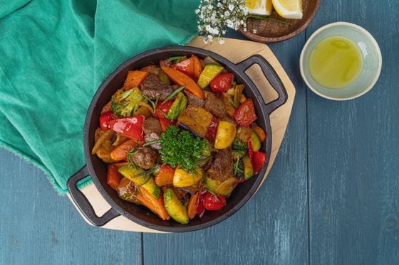 Cast iron pan of beef chunks with roasted peppers, zucchini, carrots, broccoli and parsley