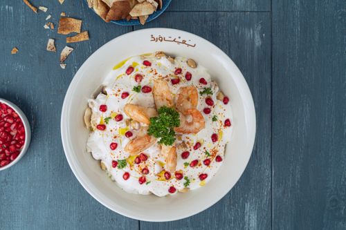 Free Aerial view of a Middle Eastern shrimp dish with pomegranate on a wooden table. Stock Photo