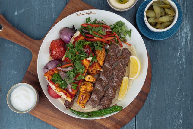 Delicious Middle Eastern platter featuring grilled meats, vegetables, and fresh herbs.