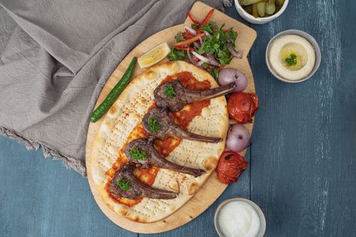 Free Savor a Middle Eastern lamb dish with flatbread, grilled vegetables, and hummus. Perfect for food enthusiasts. Stock Photo