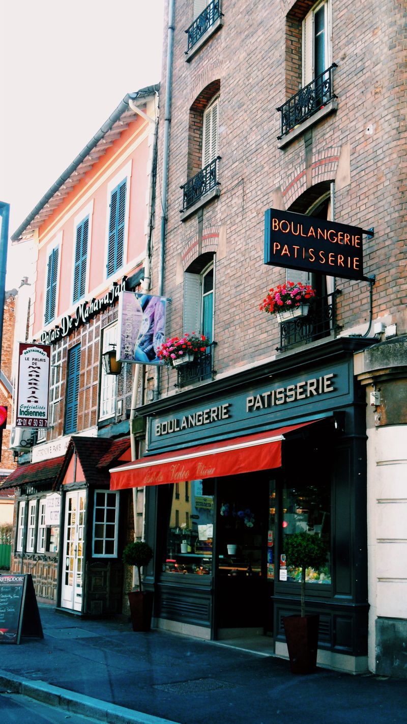 A quaint French boulangerie and patisserie with a classic facade, vibrant awning, and street view.