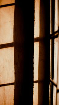 Shadow of grid of window on wooden wall in house on sunny day