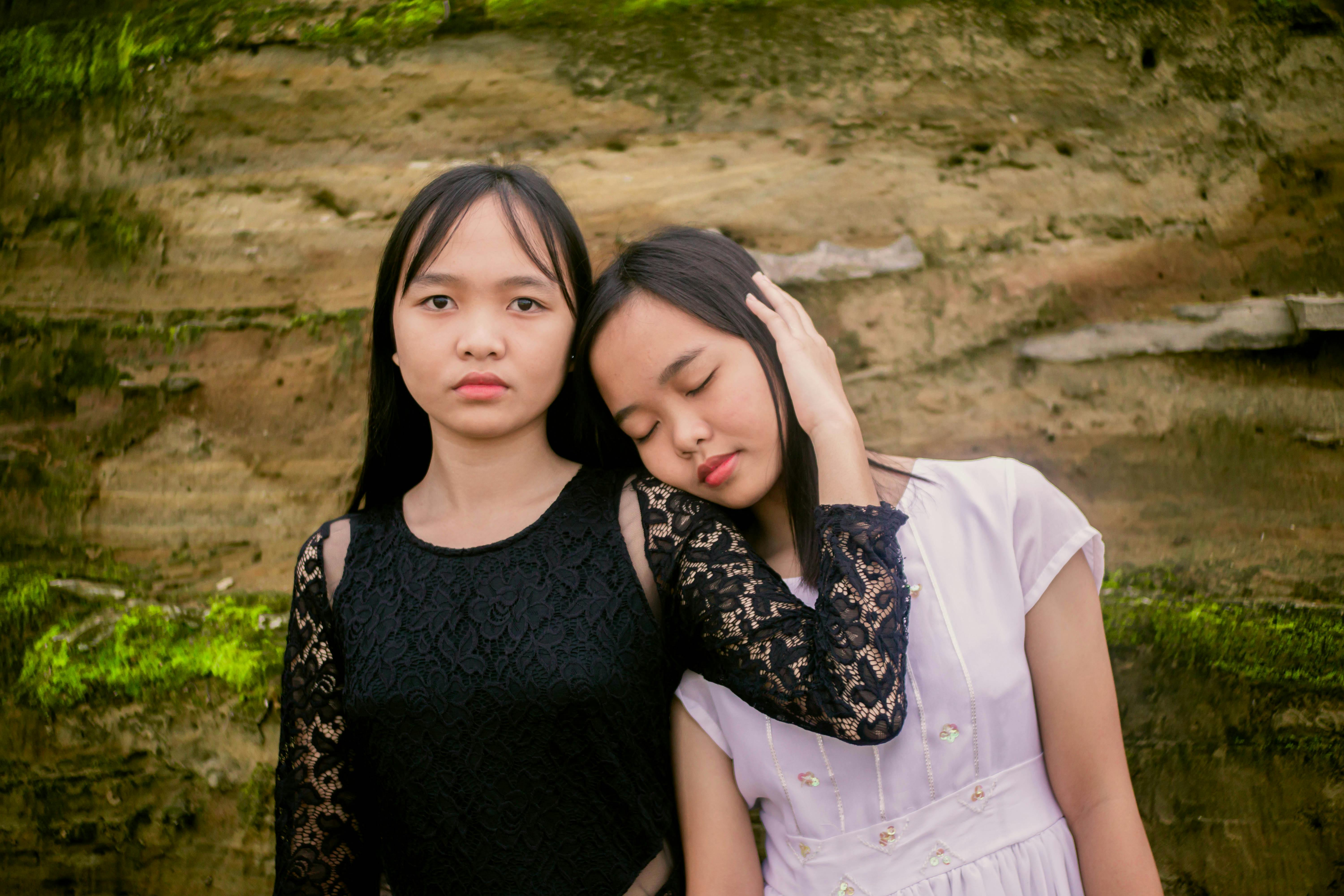 serene ethnic adolescent embracing sister in nature