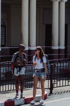 Two women travelers with backpacks smiling and enjoying a sunny day on a city street.