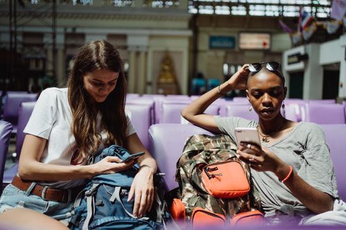 A traveller with a backpack looks up a train on his phone.