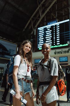 两个朋友背着背包，在火车站微笑着准备出发