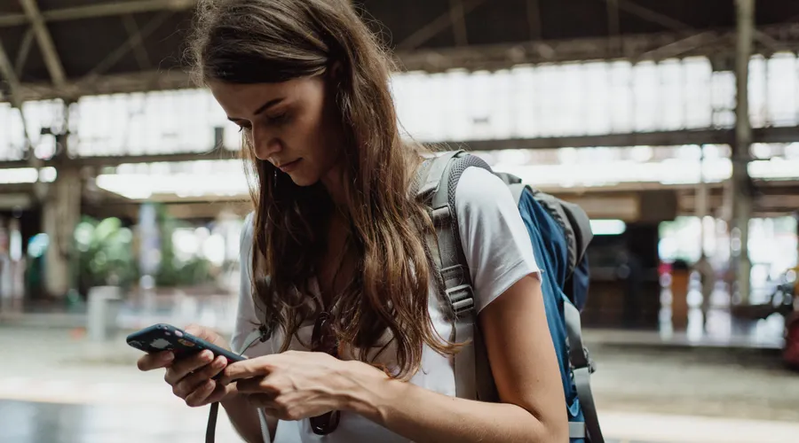 Backpacker checking her smartphone at a train station