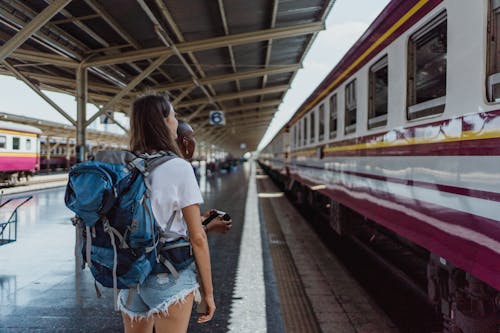 Woman in White Shirt and Blue Denim Shorts Standing at the Train Station