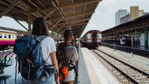 Two backpackers waiting at a railway station, ready for their travel adventure.