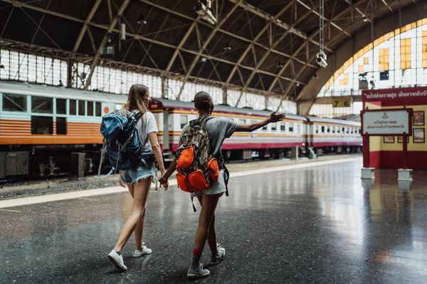 Two travellers with backpacks walking through a railway station — photo by Ketut Subiyanto on Pexels