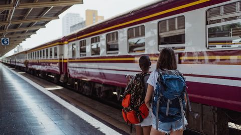 Two women with backpacks waiting at a railway platform, ready for an adventure.