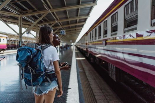 两个女人背着背包，在火车站站台上等待下一次旅行