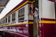 Woman in White and Red Striped Long Sleeve Shirt Standing Beside Red and Yellow Train during