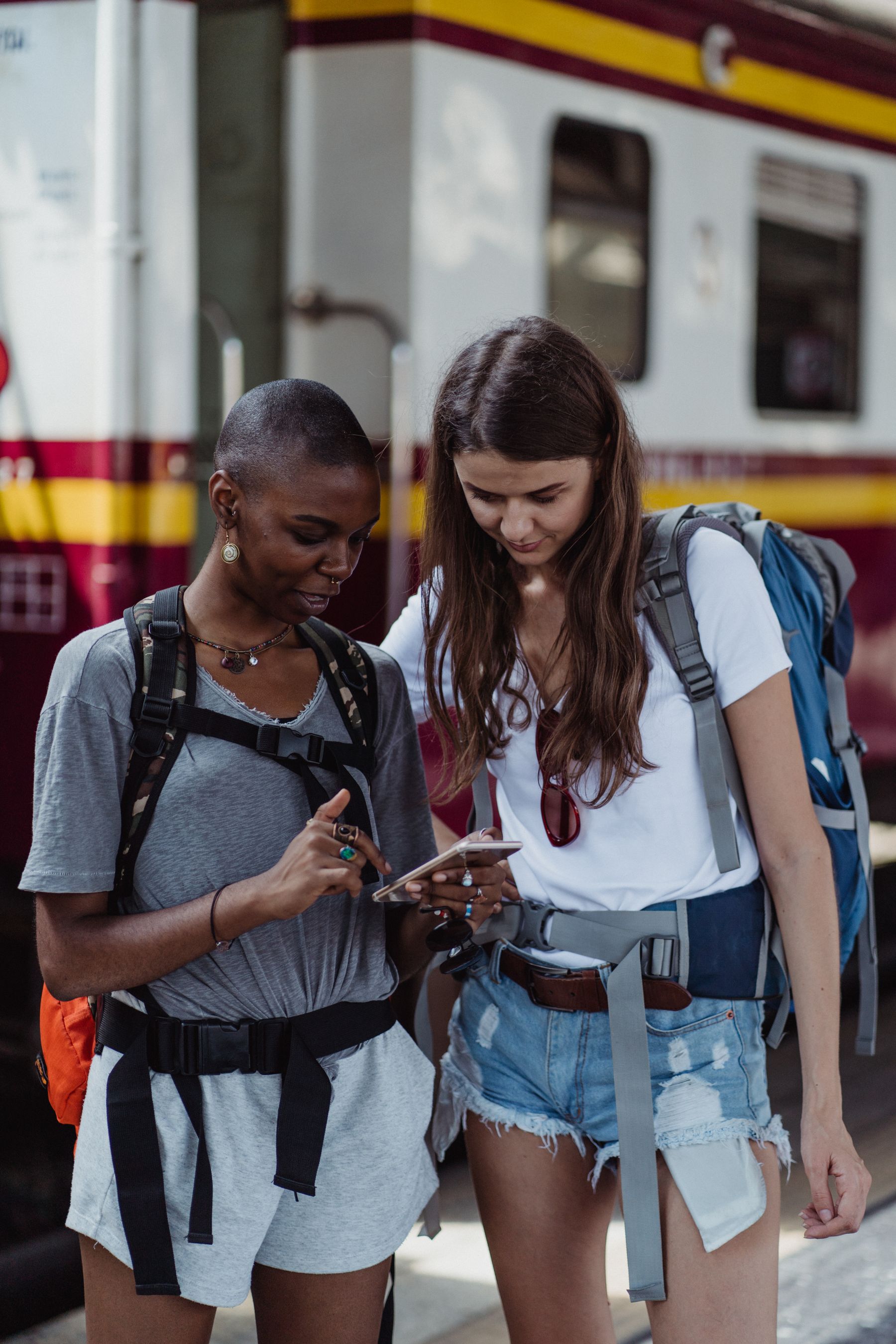 Two travelers checking a smartphone at a train station
