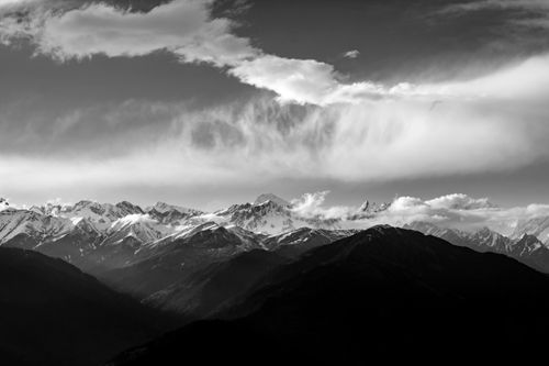 Free Captivating black and white photograph of a snowcapped mountain range under dramatic clouds. Stock Photo