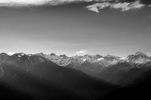 Free Black and white image of a breathtaking mountain range with snow-capped peaks and dramatic lighting. Stock Photo