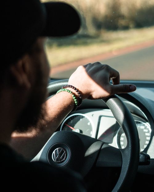 Free A man driving a Volkswagen car on a sunny day focusing on the road ahead. Stock Photo