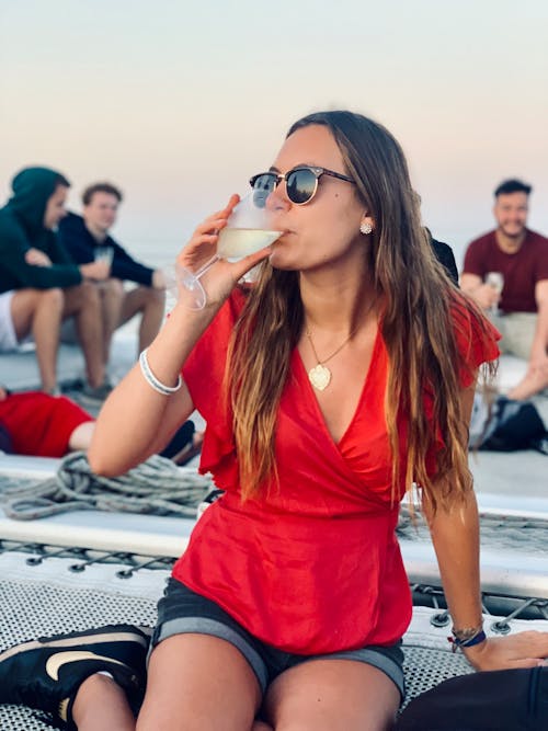 Woman in Red V Neck Shirt and Black Sunglasses Drinking Wine